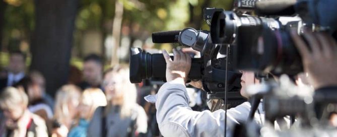 Multiple video cameramen at an outdoor event filming