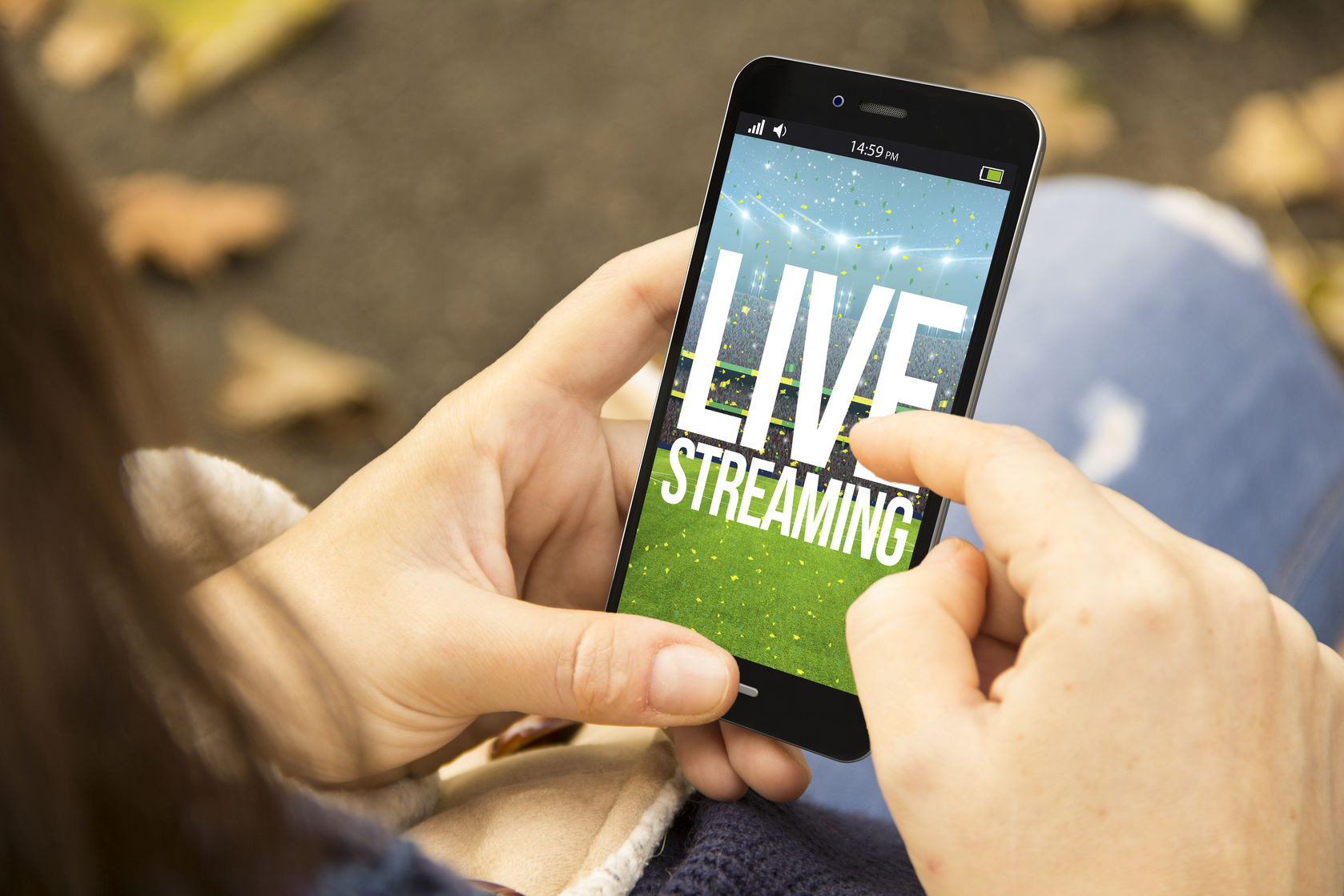 Live video streaming. A person holding their mobile phone upright whilst interacting with the touch screen