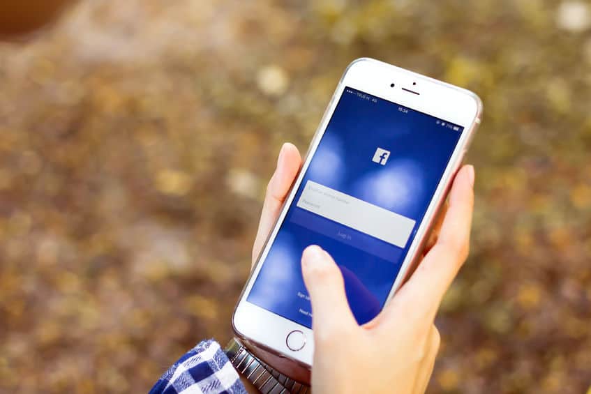 Live stream to multiple platforms A person holding their mobile phone upright whilst interacting with the touch screen