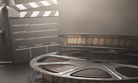 Two film reels in the foreground with a clapper board in the background.