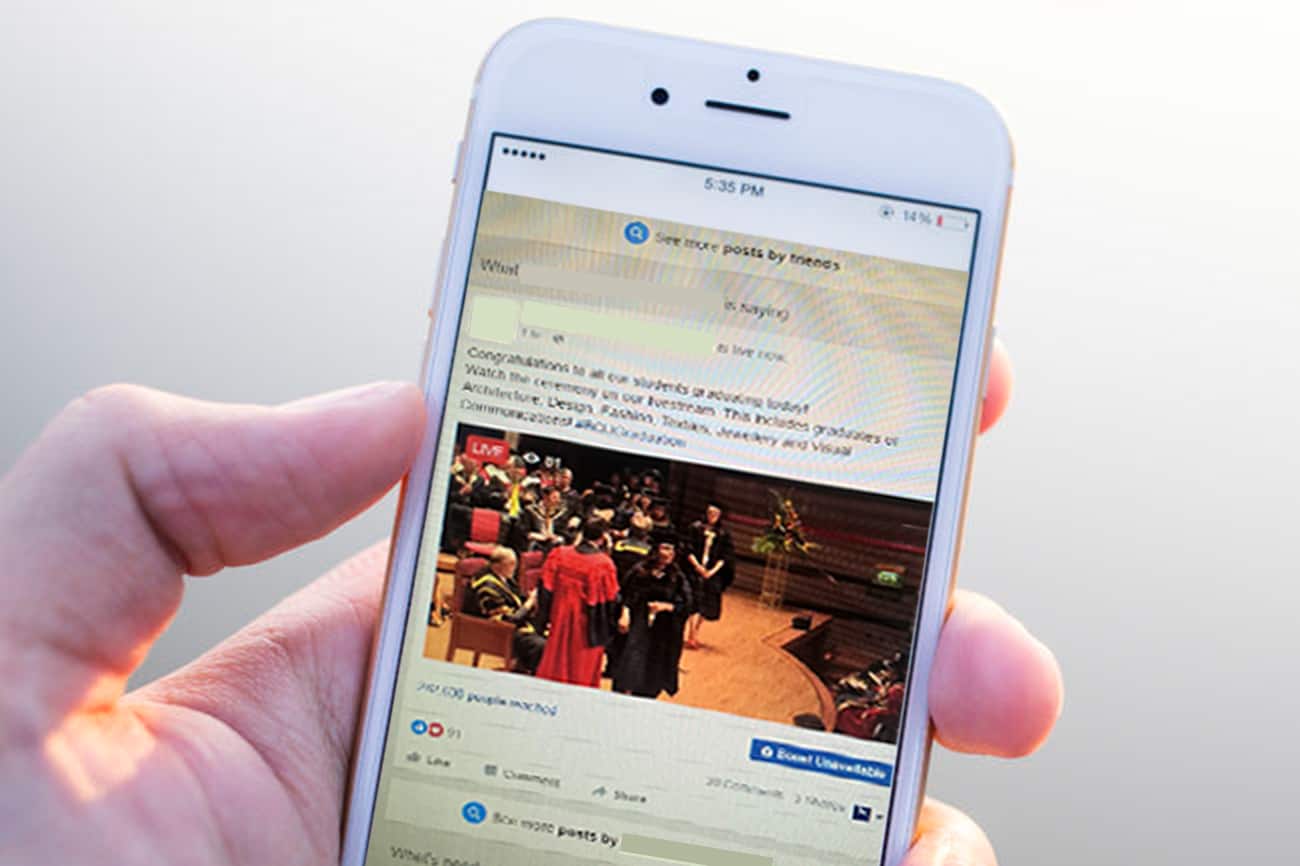 A mobile phone in a users hand. The phone screen shows a popular social media site.
