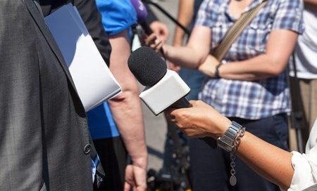 An interviewer holding a microphone towards the interviewee.